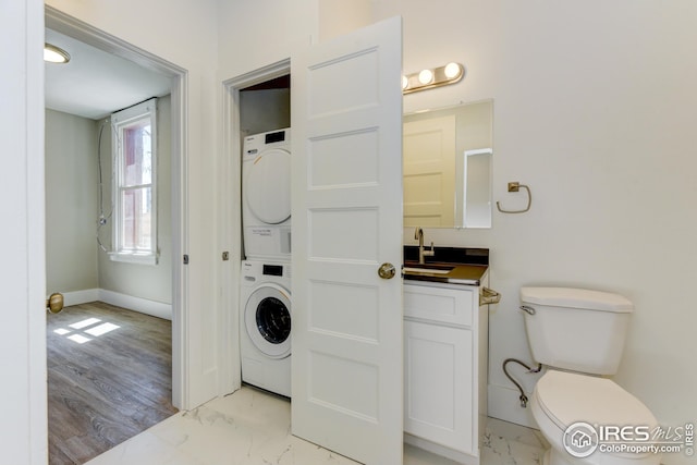 1110 13th St, Boulder, CO 80302 - bathroom featuring stacked washer / drying machine, marble finish flooring, vanity, baseboards, and toilet