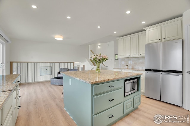 kitchen featuring appliances with stainless steel finishes, green cabinets, light wood-style flooring, white cabinets, and a kitchen island