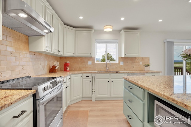 kitchen with stainless steel electric range, exhaust hood, a sink, light wood finished floors, and white cabinets