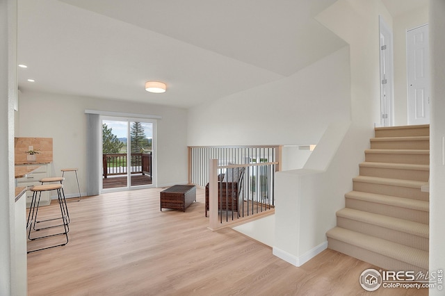 staircase with wood finished floors, baseboards, and recessed lighting