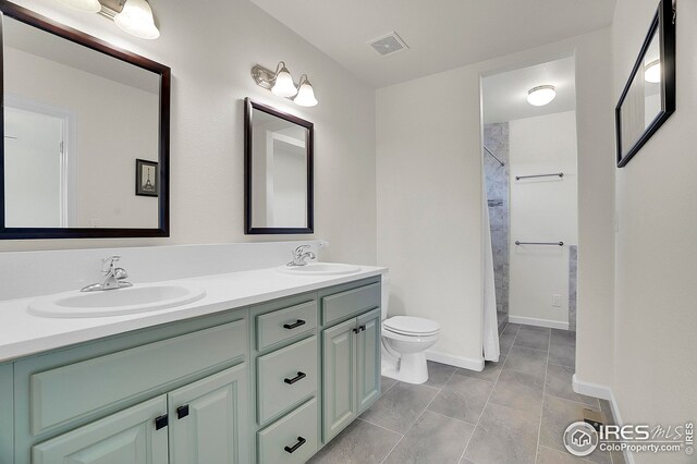 full bathroom with toilet, double vanity, baseboards, and a shower