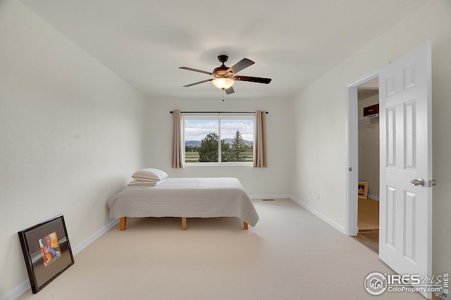 carpeted bedroom featuring baseboards, ceiling fan, and a walk in closet
