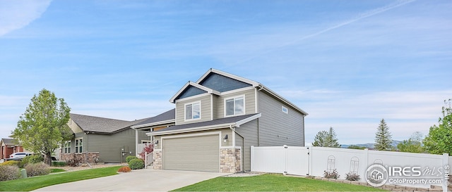 view of front of house with driveway, a garage, stone siding, and a gate