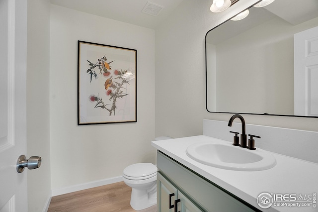bathroom featuring wood finished floors, vanity, toilet, and baseboards