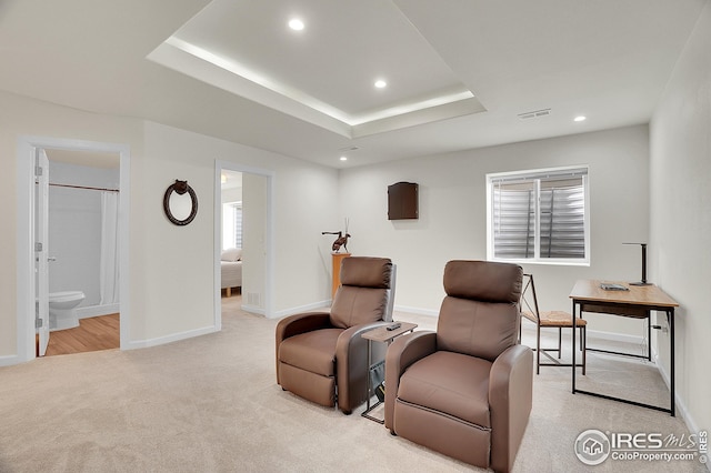 sitting room with light colored carpet, recessed lighting, baseboards, and a tray ceiling