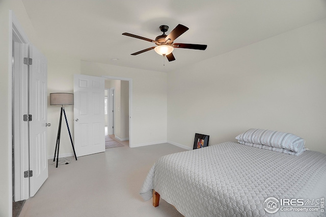bedroom featuring light carpet, baseboards, and a ceiling fan