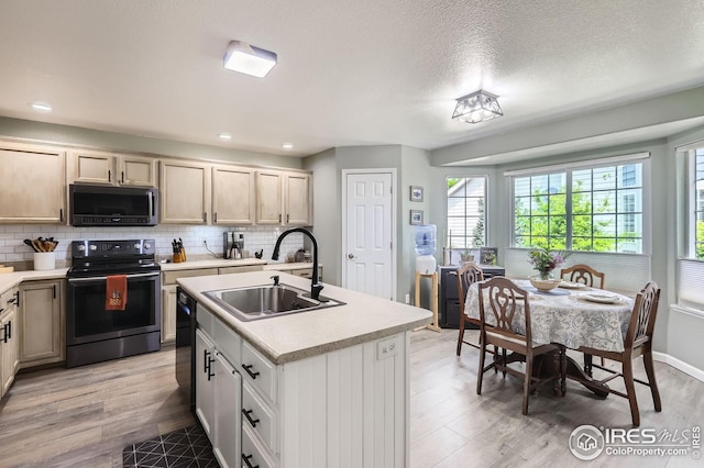kitchen featuring electric range, a sink, light countertops, light wood-style floors, and recessed lighting