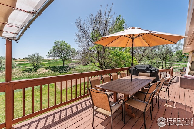 wooden terrace featuring outdoor dining area and a lawn