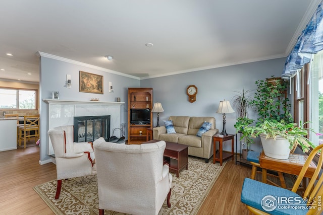 living room featuring light wood-style floors, a high end fireplace, crown molding, and recessed lighting