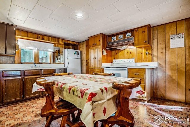 2450 Eagle Cliff Rd, Estes Park, CO 80517 - kitchen with white appliances, brick floors, wooden walls, under cabinet range hood, and light countertops