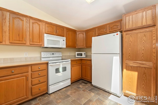 955 Sunchase Dr, Fort Collins, CO 80524 - kitchen with white appliances, vaulted ceiling, light countertops, stone finish floors, and brown cabinetry