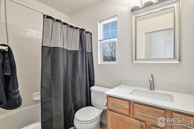 bathroom featuring toilet, vanity, shower / tub combo with curtain, and a textured wall