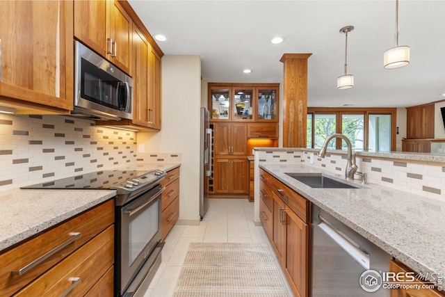 1140 Portland Pl Unit 207, Boulder, CO 80304 - kitchen with stainless steel appliances, a sink, brown cabinetry, light tile patterned floors, and tasteful backsplash