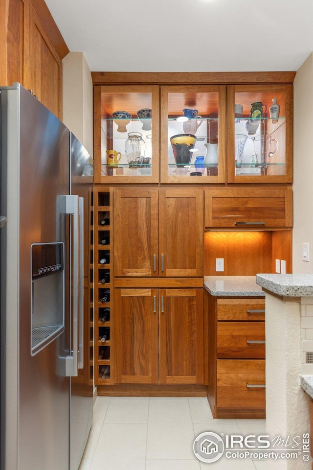 1140 Portland Pl Unit 207, Boulder, CO 80304 - kitchen view of stainless steel fridge, brown cabinetry, light stone counters, and glass insert cabinets