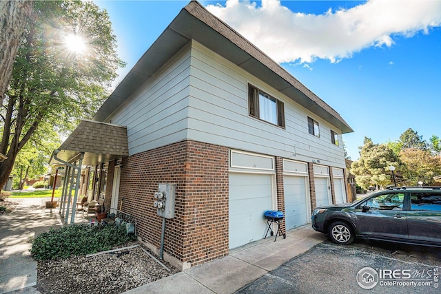1001 Strachan Dr Unit 24, Fort Collins, CO 80525 - view of home's exterior featuring an attached garage, driveway, and brick siding