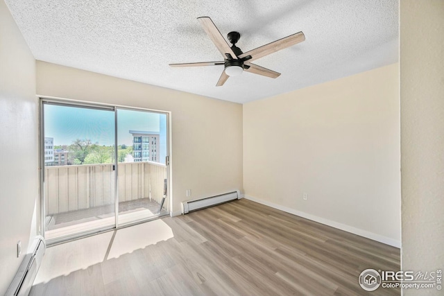 empty room featuring baseboard heating, wood finished floors, a ceiling fan, a textured ceiling, and baseboards