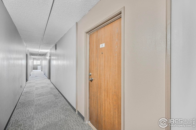 corridor featuring a textured ceiling and carpet floors