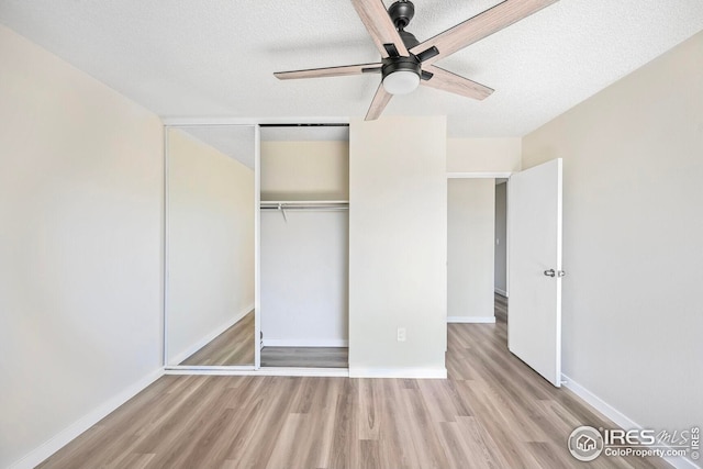 unfurnished bedroom with wood finished floors, a textured ceiling, a closet, baseboards, and a ceiling fan