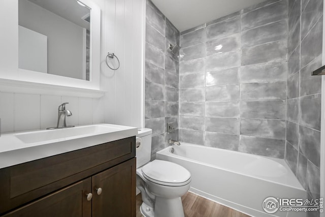 bathroom with toilet, wood finished floors, shower / bathtub combination, and vanity