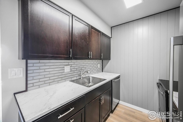 kitchen with a sink, light wood-type flooring, dishwasher, decorative backsplash, and dark brown cabinetry