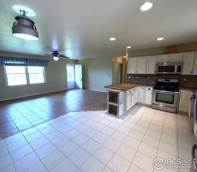22198 County Road 25, Fort Morgan, CO 80701 - kitchen with stainless steel appliances, light tile patterned floors, white cabinets, open floor plan, and backsplash