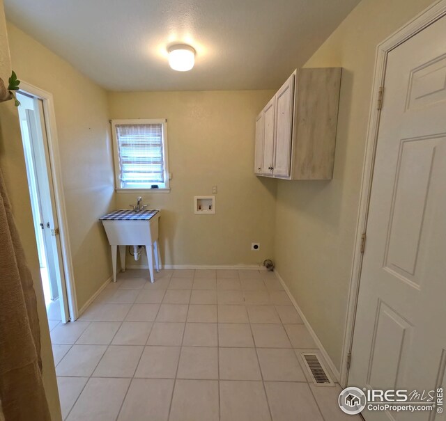 22198 County Road 25, Fort Morgan, CO 80701 - laundry room featuring washer hookup, electric dryer hookup, cabinet space, and light tile patterned floors