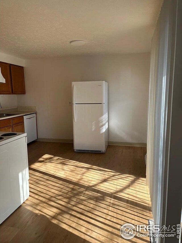 712 Meeker St, Longmont, CO 80504 - kitchen featuring white appliances, wood finished floors, baseboards, brown cabinets, and a sink