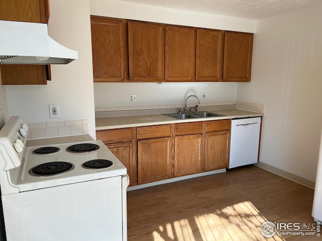 712 Meeker St, Longmont, CO 80504 - kitchen featuring white appliances, a sink, under cabinet range hood, brown cabinetry, and wood finished floors