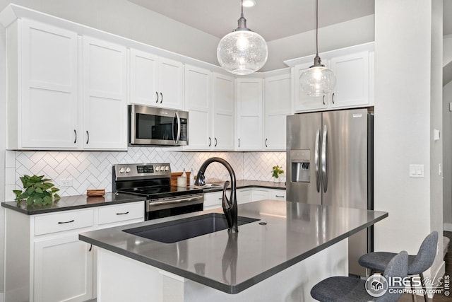 2497 Trio Falls Dr, Loveland, CO 80538 - kitchen featuring stainless steel appliances, dark countertops, a breakfast bar area, decorative backsplash, and white cabinetry