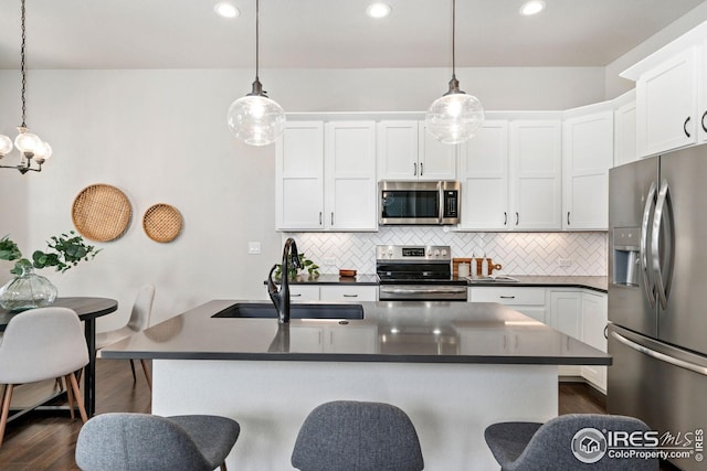 2497 Trio Falls Dr, Loveland, CO 80538 - kitchen featuring stainless steel appliances, a sink, dark countertops, dark wood-type flooring, and decorative backsplash