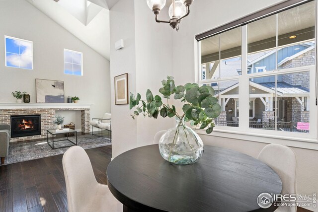 2497 Trio Falls Dr, Loveland, CO 80538 - dining room featuring high vaulted ceiling, dark wood-style flooring, a brick fireplace, and a chandelier