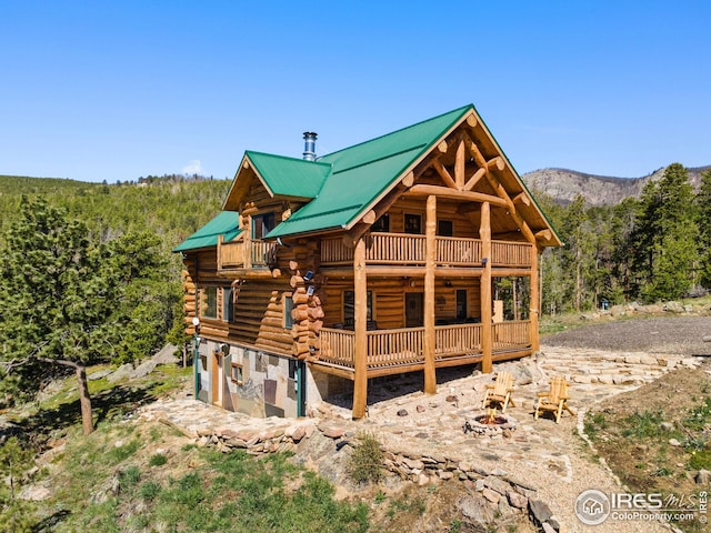77 Cairn Ct, Drake, CO 80515 - rear view of property featuring log exterior, a fire pit, metal roof, stone siding, and a view of trees