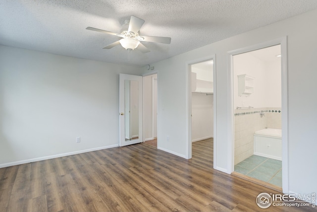 2620 Lloyd Cir, Boulder, CO 80304 - unfurnished bedroom featuring wood finished floors, a walk in closet, a closet, a textured ceiling, and ensuite bathroom