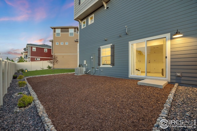 542 Highlands Cir, Erie, CO 80516 - back of property at dusk featuring a fenced backyard and central AC
