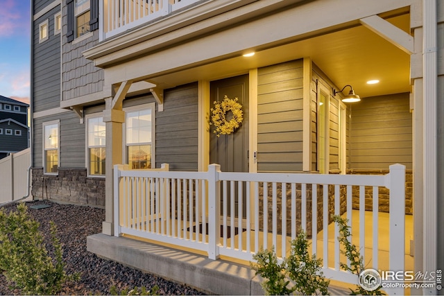 542 Highlands Cir, Erie, CO 80516 - exterior entry at dusk featuring a porch, stone siding, and a balcony