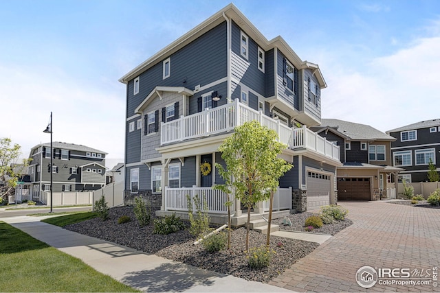542 Highlands Cir, Erie, CO 80516 - view of front facade with a balcony, stone siding, a porch, and driveway