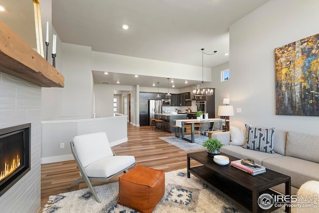 6752 Castello St, Timnath, CO 80547 - living room featuring a fireplace, light wood finished floors, recessed lighting, a chandelier, and baseboards