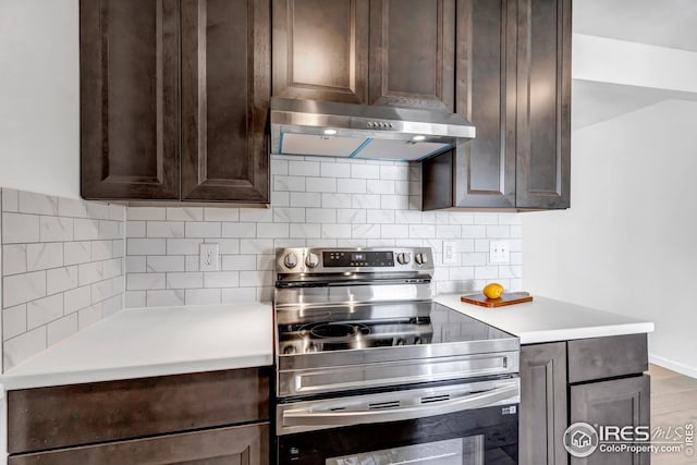 1006 4th St, Pierce, CO 80650 - kitchen featuring stainless steel electric range, dark brown cabinets, under cabinet range hood, light countertops, and backsplash