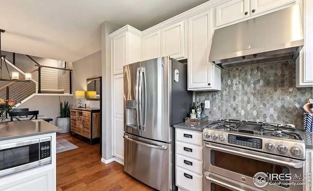 2639 County Fair Ln, Fort Collins, CO 80528 - kitchen with stainless steel appliances, under cabinet range hood, wood finished floors, white cabinetry, and backsplash