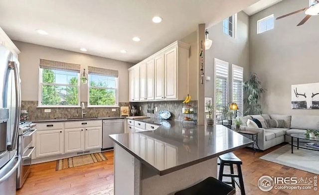 2639 County Fair Ln, Fort Collins, CO 80528 - kitchen featuring stainless steel appliances, a sink, dark countertops, white cabinets, and a breakfast bar