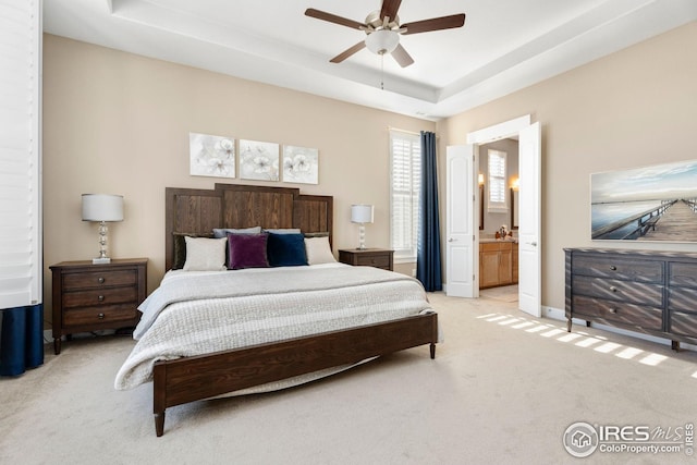 1030 Larimer Ridge Pkwy, Timnath, CO 80547 - bedroom with light carpet, a tray ceiling, connected bathroom, and ceiling fan