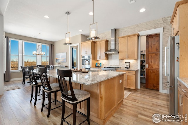 1030 Larimer Ridge Pkwy, Timnath, CO 80547 - kitchen with wall chimney range hood, stainless steel appliances, light wood-type flooring, a breakfast bar, and recessed lighting
