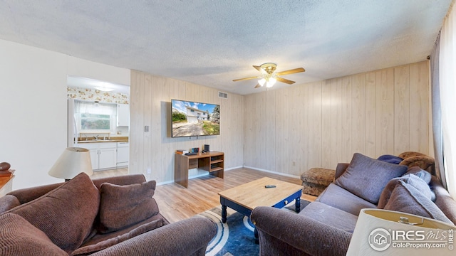 8208 Peakview Dr, Fort Collins, CO 80528 - living area featuring light wood-style floors, a ceiling fan, baseboards, a textured ceiling, and wood walls