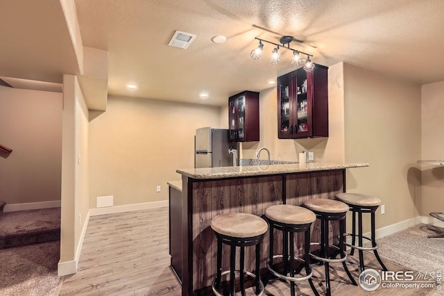 405 Timber Ridge Pkwy, Severance, CO 80550 - indoor wet bar featuring freestanding refrigerator, a textured ceiling, baseboards, and light wood-style flooring