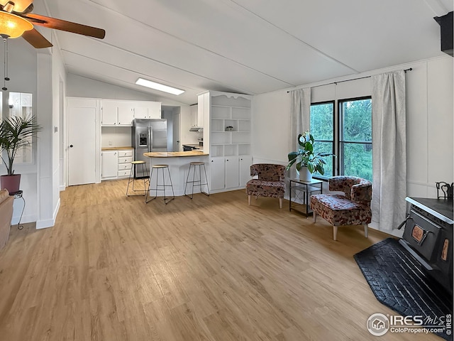 306 E Arapahoe St, Fleming, CO 80728 - living area featuring a wood stove, vaulted ceiling, light wood-style flooring, and a ceiling fan