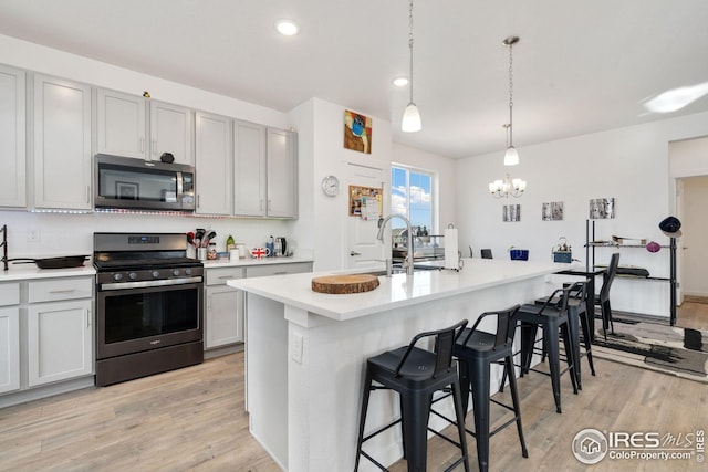 1958 Autumn Moon Dr, Windsor, CO 80550 - kitchen with stainless steel appliances, a chandelier, light wood-style floors, a kitchen bar, and light countertops