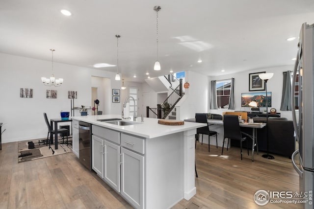 1958 Autumn Moon Dr, Windsor, CO 80550 - kitchen featuring appliances with stainless steel finishes, an island with sink, light wood-type flooring, light countertops, and decorative light fixtures