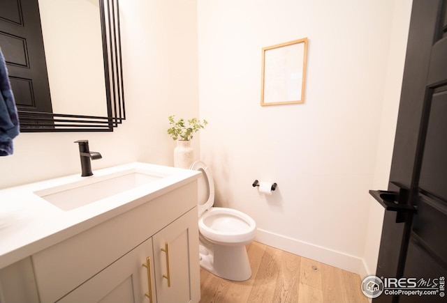 9415 E 58th Dr, Denver, CO 80238 - bathroom featuring vanity, baseboards, wood finished floors, and toilet