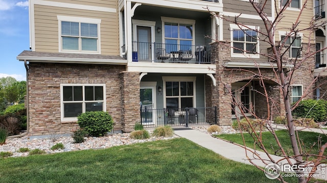4642 Hahns Peak Dr Unit 101, Loveland, CO 80538 - view of front of house with a balcony, covered porch, stone siding, and a front lawn