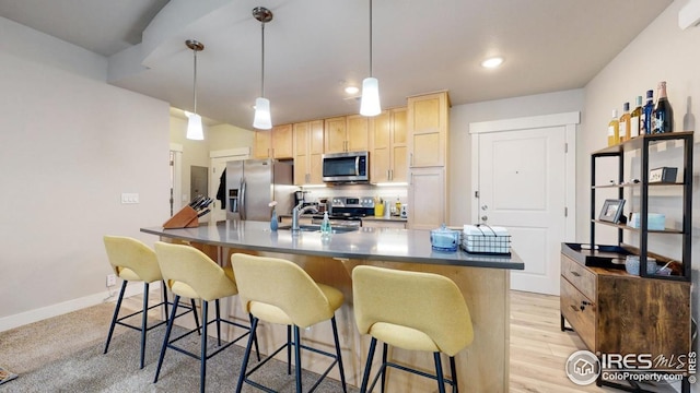 4642 Hahns Peak Dr Unit 101, Loveland, CO 80538 - kitchen featuring stainless steel appliances, a sink, light brown cabinets, an island with sink, and a breakfast bar
